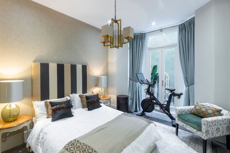 Bedroom with a striped headboard and doors to the garden