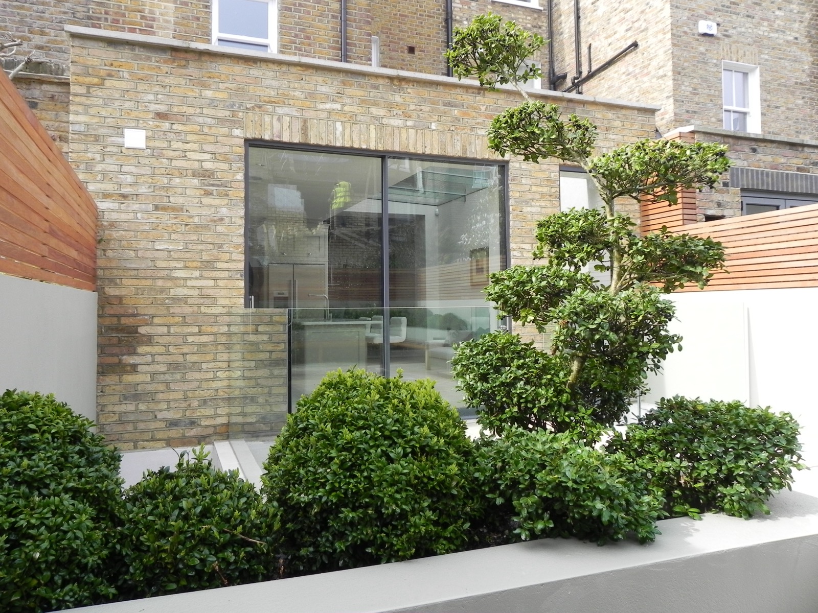 Brick rear extension with sliding doors and a planted terrace