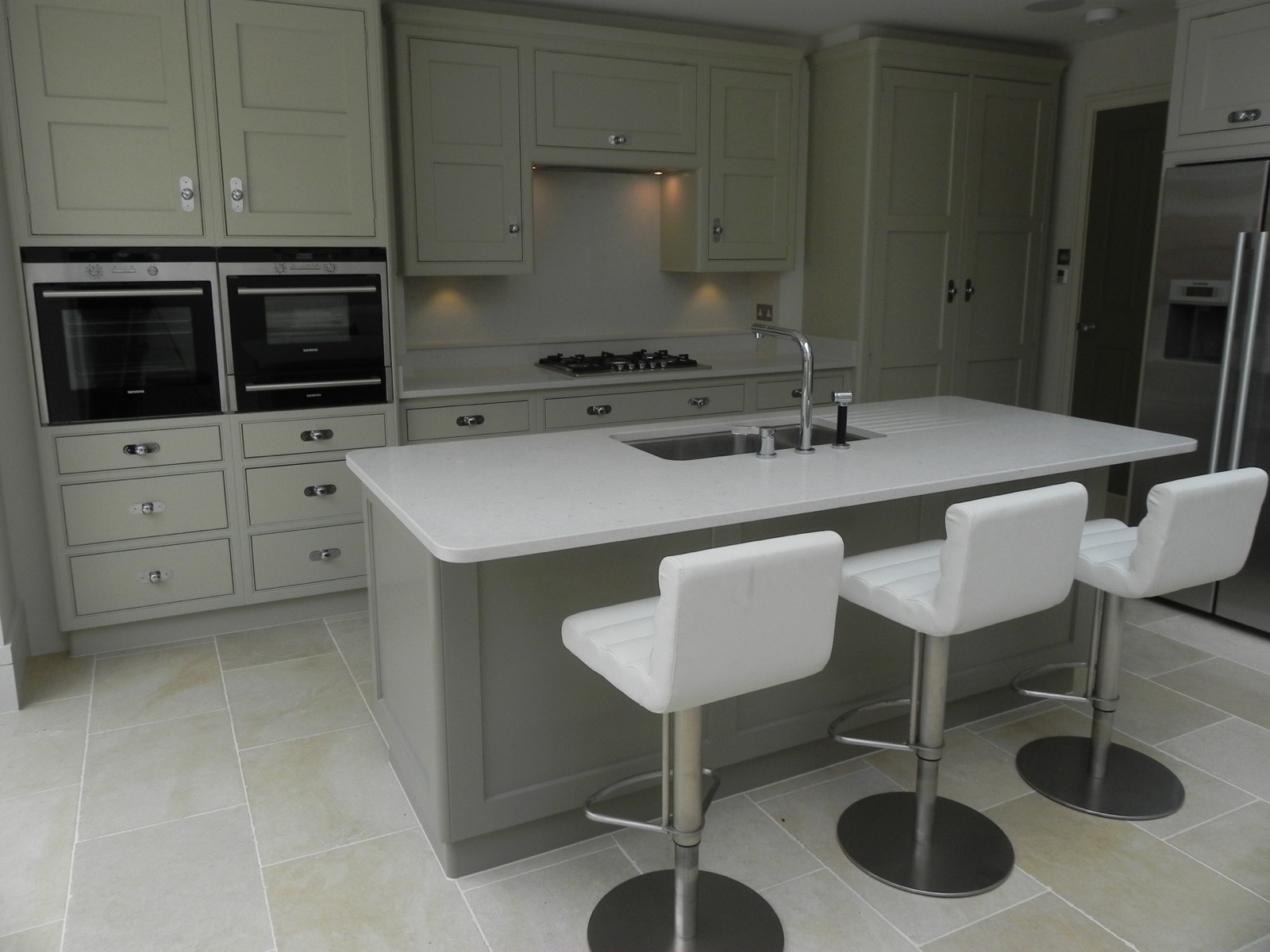 Sage green kitchen with an island and bar stools