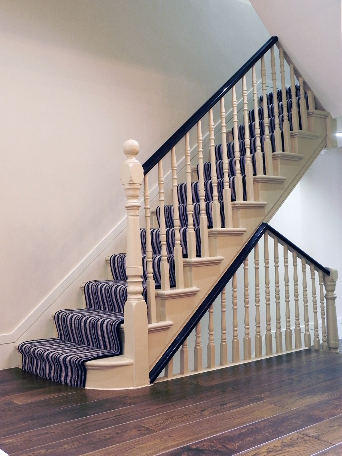 Staircase with painted spindles and a striped runner