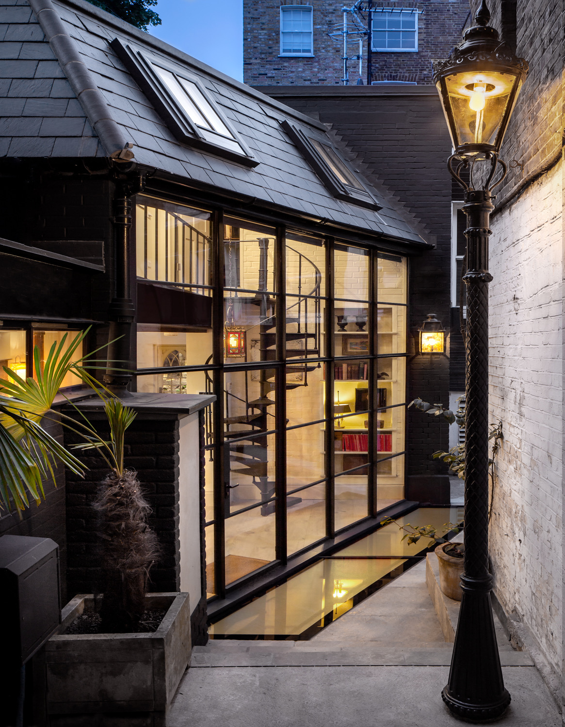 Steel-framed glazed extension lit at dusk