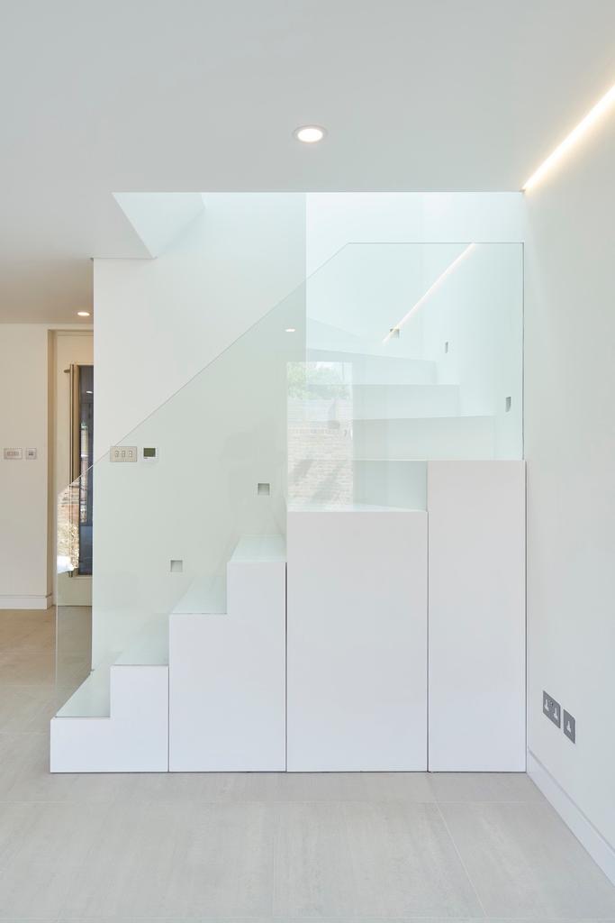 White staircase with a glass balustrade and built-in storage