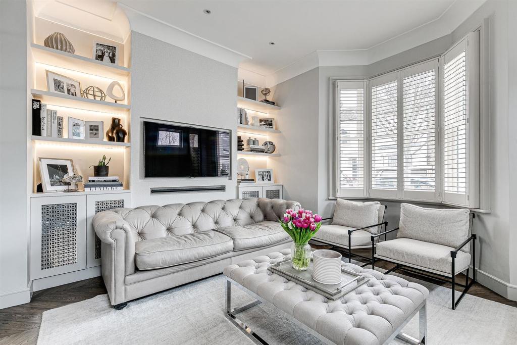 Living room with lit bespoke shelving and plantation shutters, design and build in East London and Essex
