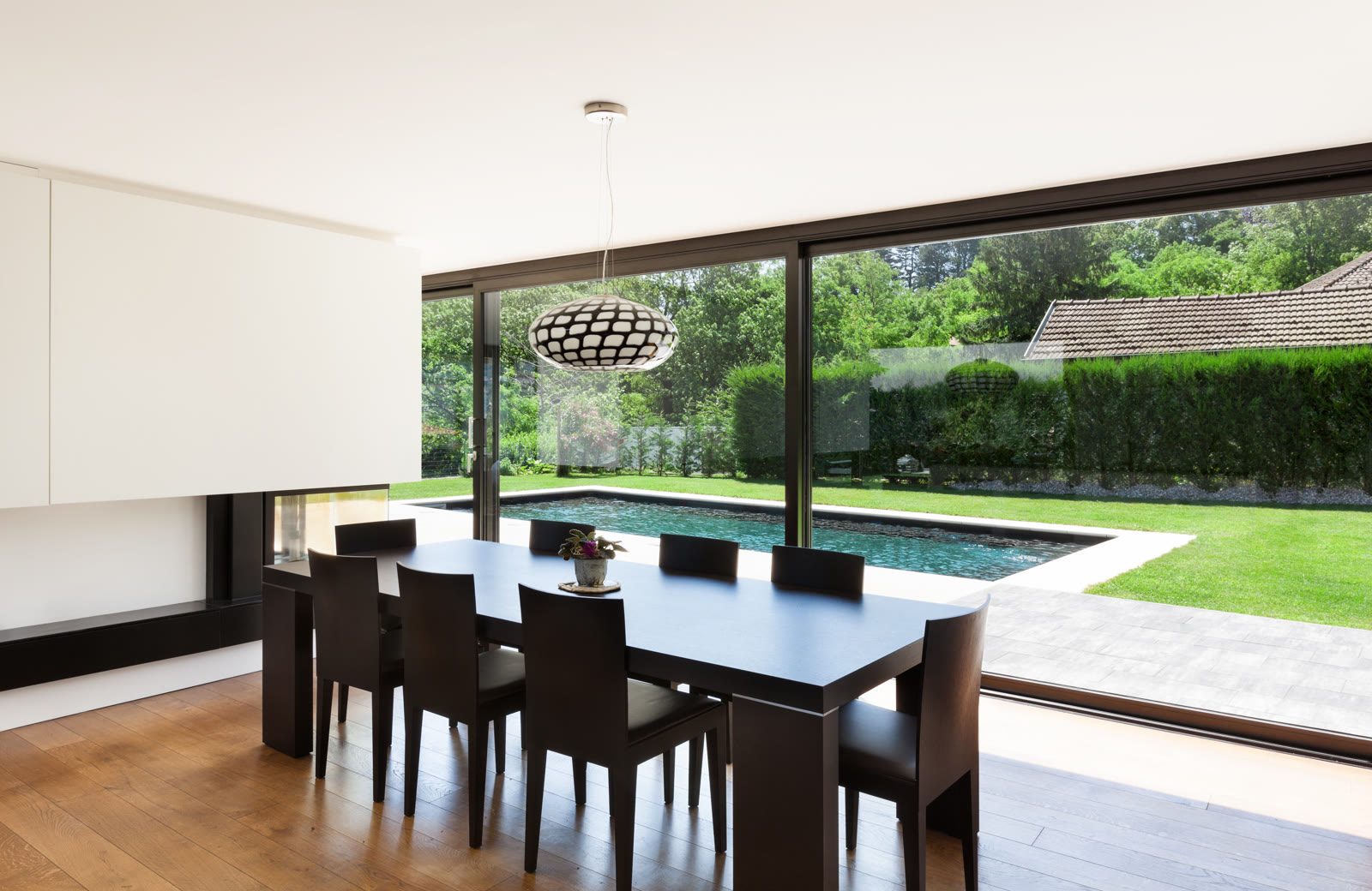 Dining room with full-height glazing onto the garden and pool in Chigwell