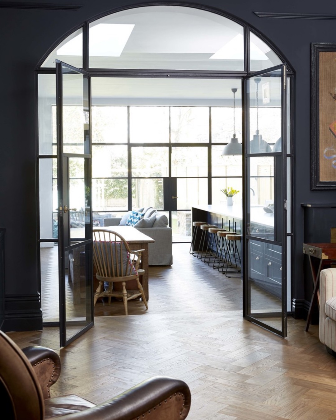 Arched steel-framed doors opening from a reception room into a kitchen extension