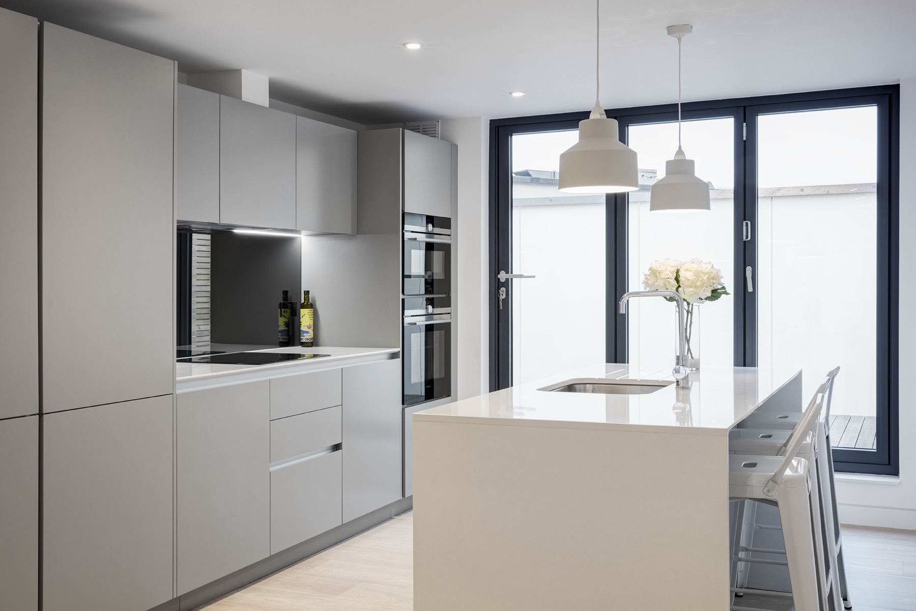 Kitchen island with bifold doors to a terrace, kitchen extension in Barking and Dagenham