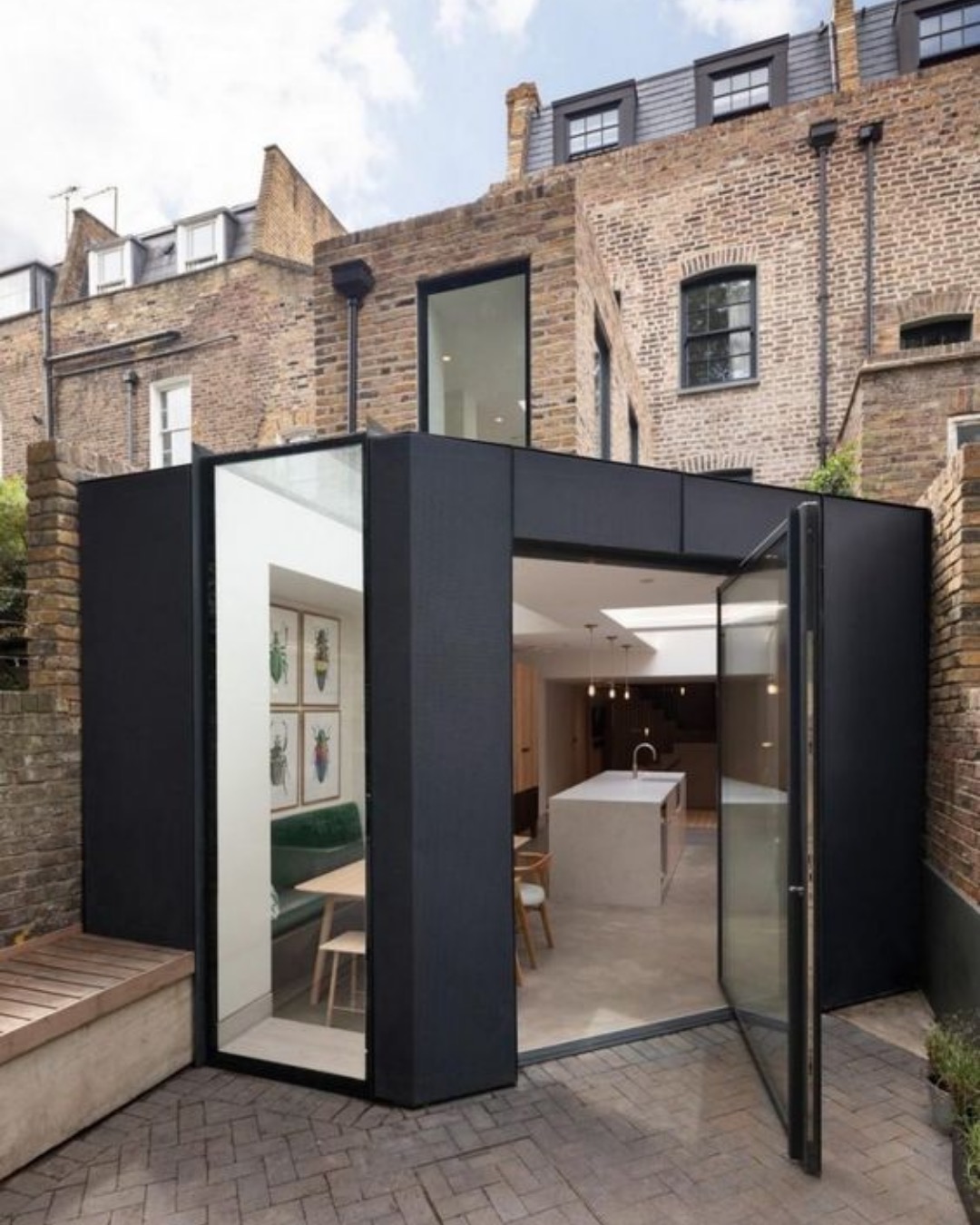 Black-framed rear extension with a large glass pivot door in a small walled garden