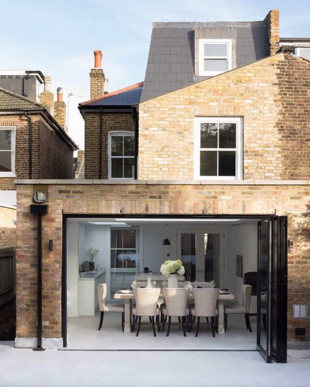 Brick rear extension with bifold doors open to a dining room
