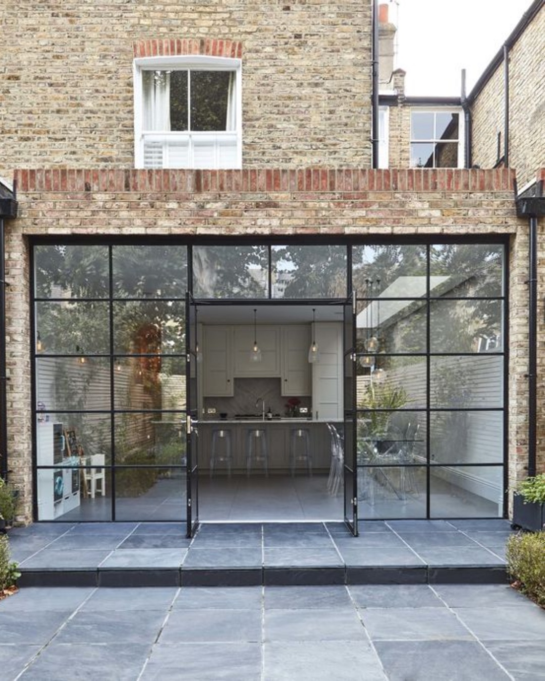 Brick rear extension with full-width steel-framed glazing and a slate terrace