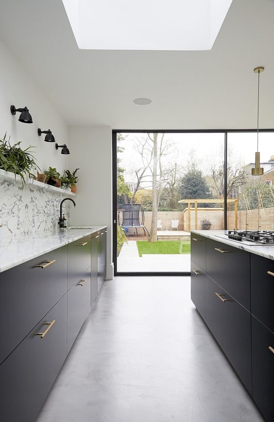 Dark handleless kitchen with a large rooflight and a sliding door to the garden