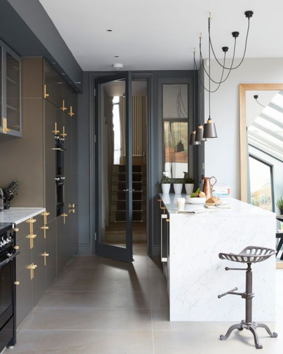 Dark kitchen with brass handles, a marble island and glazed double doors