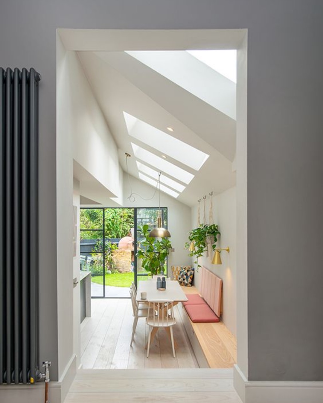 View through to a dining area under rooflights with steel-framed doors to the garden