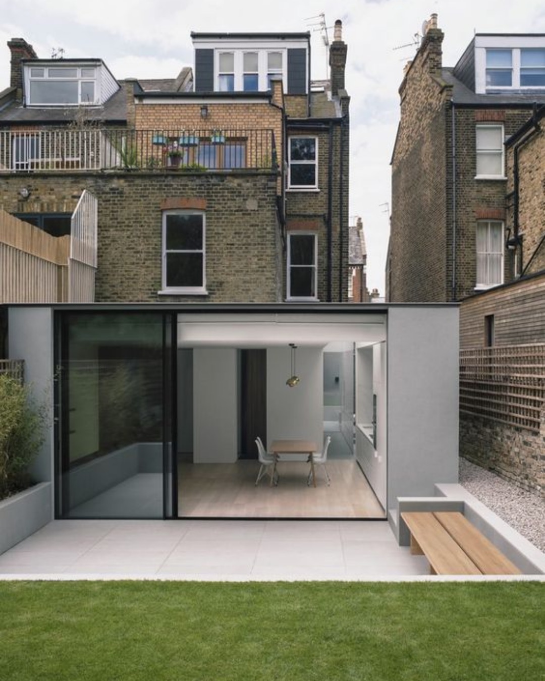 Flat-roofed rear extension with large sliding doors opening to a terrace and lawn