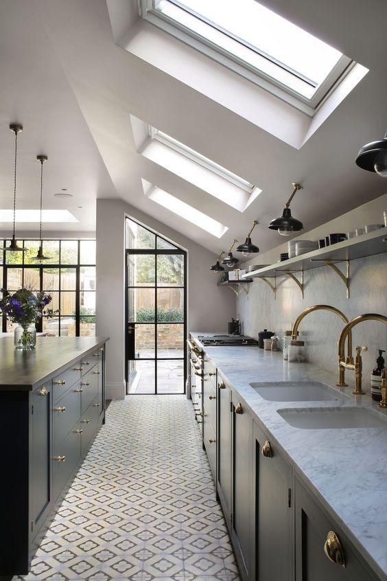 Galley kitchen under a sloping roof with rooflights, patterned floor tiles and a steel-framed door