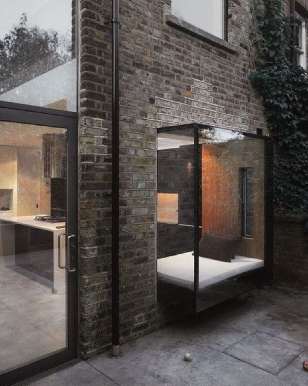 Glazed corner of a kitchen extension set into dark brickwork