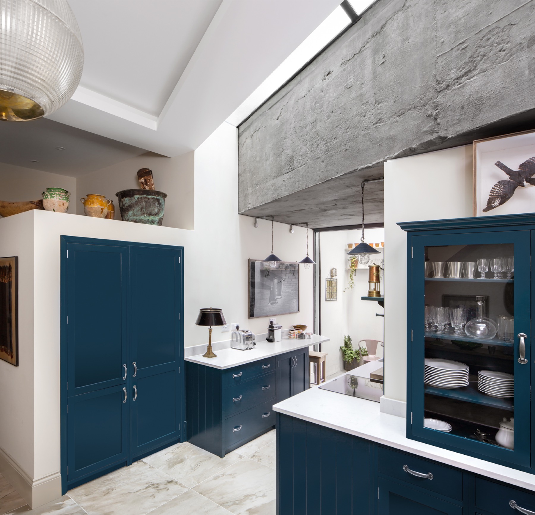 Blue shaker kitchen under a rooflight with an exposed concrete beam, kitchen extension in Hackney