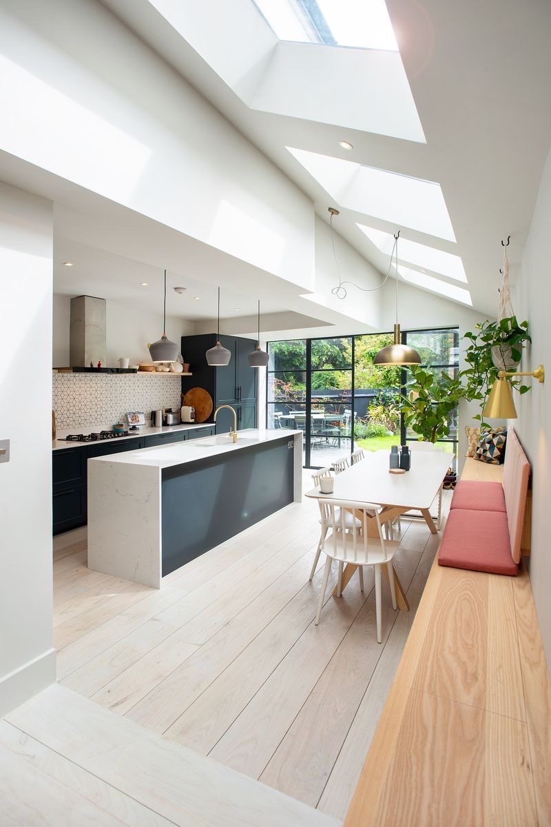 Open-plan kitchen extension with rooflights, an island, a dining table and a built-in bench