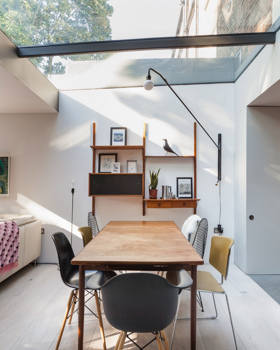 Dining table under a frameless glass roof in a side return extension