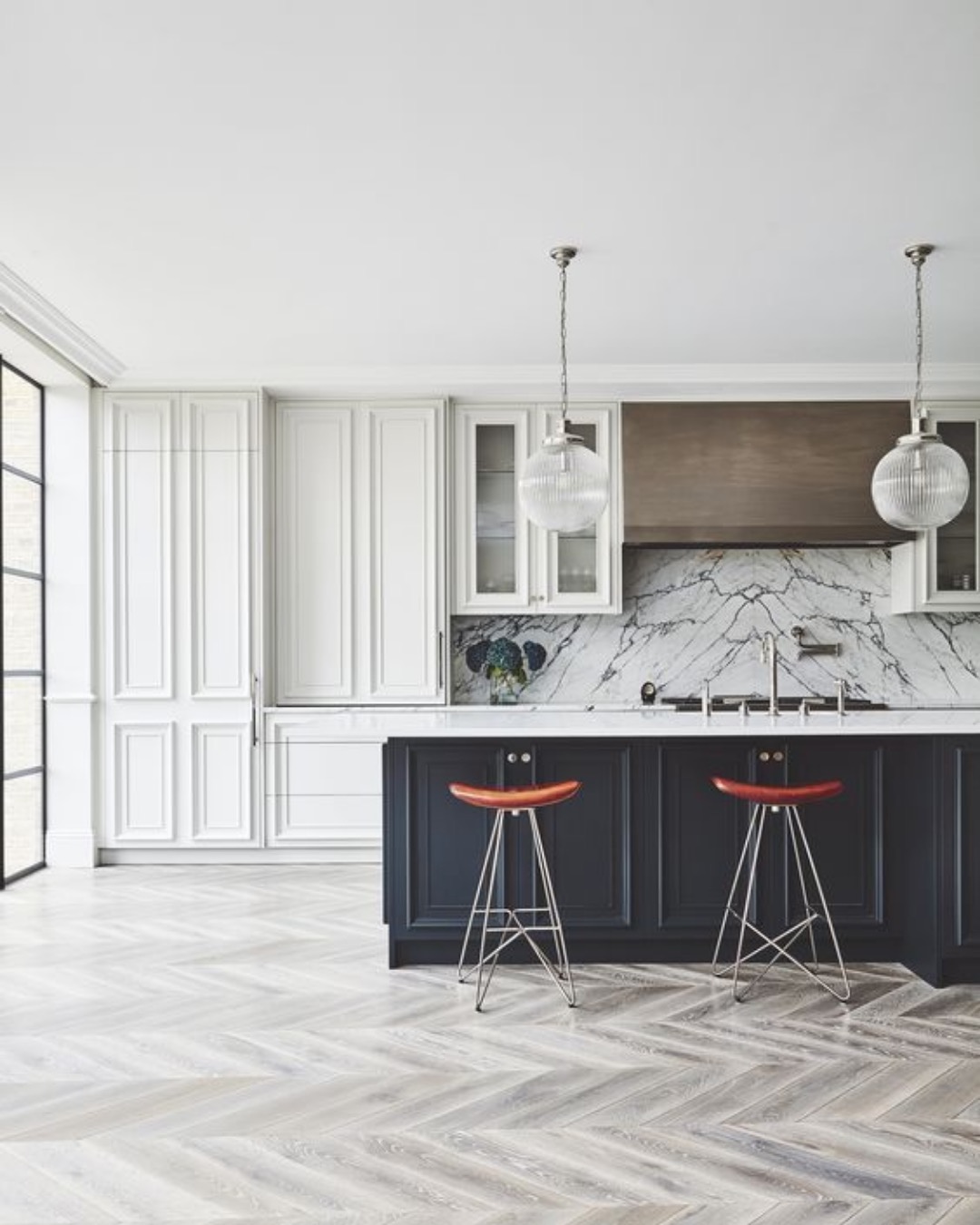 Large kitchen with white panelled cabinetry, a dark island and a herringbone floor