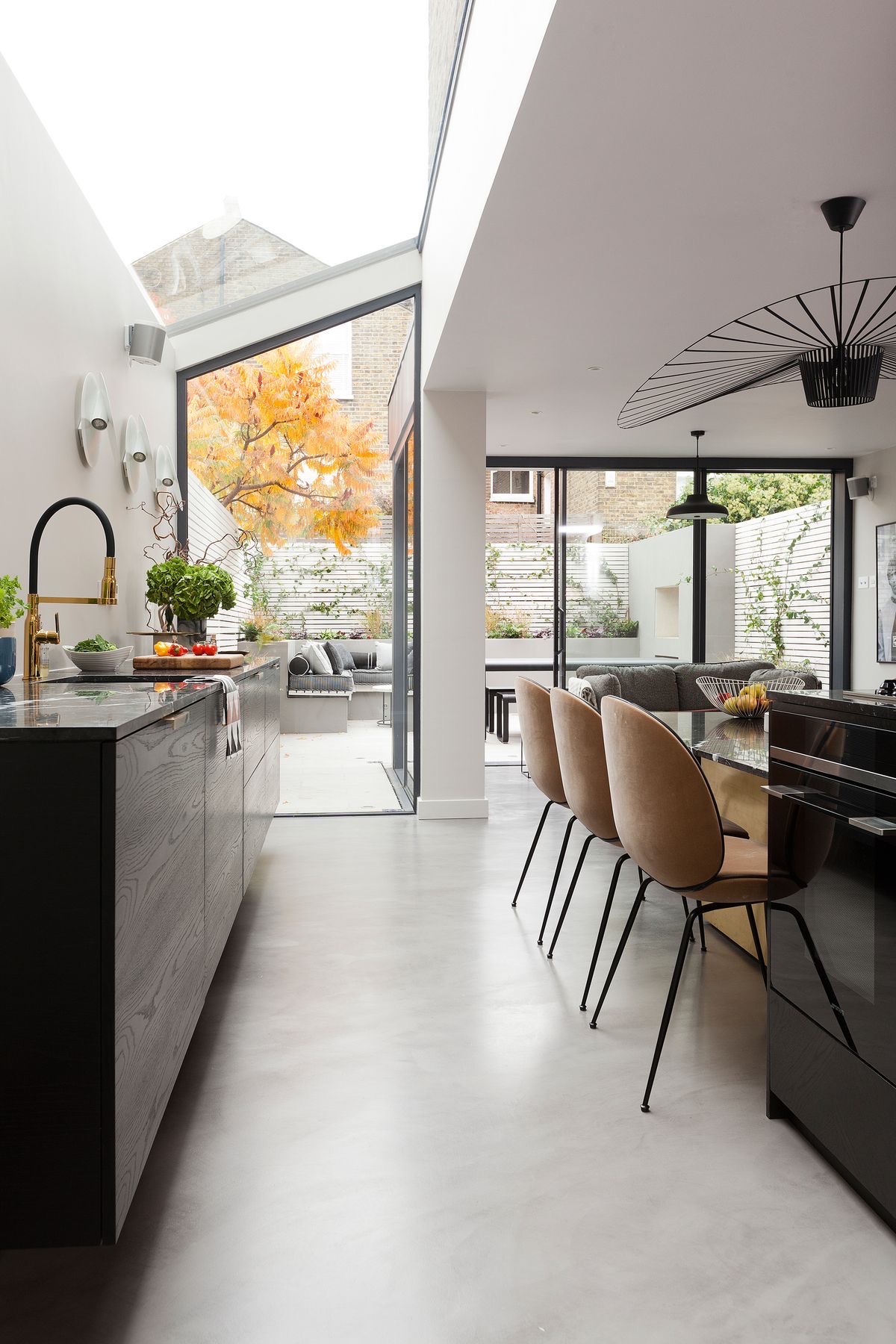 Open-plan kitchen with a polished concrete floor, island and glazing opening to a garden
